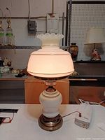 Lamp lit showing both upper and lower globes illuminated, brass base and power cord visible