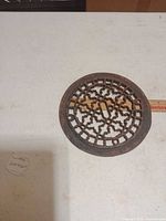 Top view of round cast iron grate showing lattice design and rust patina