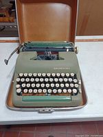 Open case showing green Smith-Corona typewriter front view
