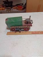 Left side view showing green cab, red chassis, metal treads and scale ruler