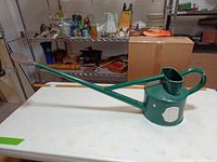 Full view of green Haws watering can on table