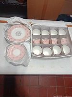 Stacked pie plates and saucers beside boxed teacups