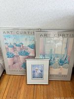 three framed prints leaning against wall