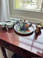 Group shot showing complete tea set with six cups, teapot on underplate, two vases