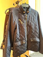 Front view navy Mountain Horse quilted jacket on hanger, brown Tempo jacket partially visible behind