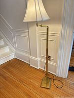 Full view of brass floor lamp beside wall and staircase