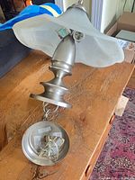 Full view of hanging light showing metal body, glass shade, canopy and wiring