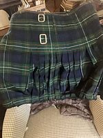 Full view of pleated tartan kilt with buckles