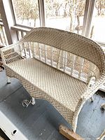 Angled view of white wicker loveseat showing overall form and arm design
