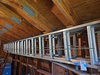 Long view of aluminum extension ladder stored under rafters