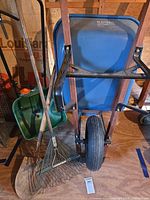 Wheelbarrow front view with spreader, rake, shovel visible