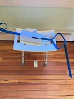 Shower seat with leg-lifter strap and brace placed on top