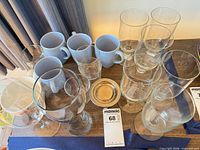 Group view of clear glassware and white mugs on tabletop