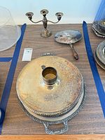 Stacked covered dish with lid, round trays beneath, showing tarnish and ornate borders