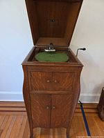 Console phonograph with lid open showing turntable, tonearm and crank