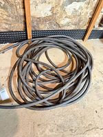 Coiled black rubber garden hose on floor