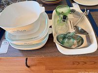 Stacked CorningWare dishes with lids and tray of glass items