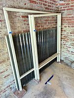 Pair of framed corrugated panels standing against brick wall