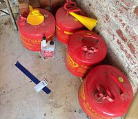 Four Eagle red metal safety cans with funnels and additive bottle