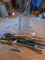 Pile of shovel, cultivator, assorted metal stakes and nested wire plant cage