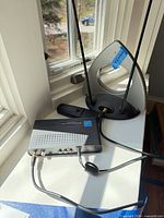 Antenna base with dipole rods connected to amplifier box and cabling on window sill