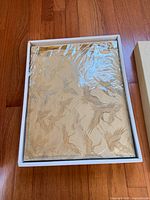 Gold fabric album inside the open presentation box, plastic wrap visible