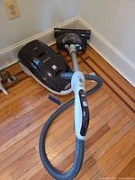 Canister vacuum with hose, wand and powered head positioned in corner