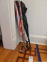 Four umbrellas leaning against wall showing patterns and handles