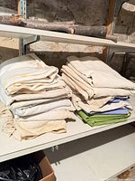 Stacks of folded off-white, green and blue canvas drop cloths on shelf