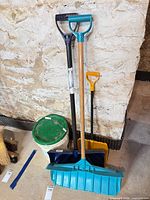 Group view of three shovels leaning against wall with bucket