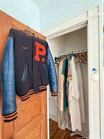 Varsity jacket hanging on door with glimpse of closet contents