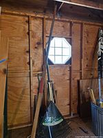 Group of long-handled garden tools leaning against shed wall