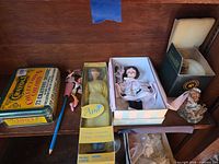 Overall view showing tin, dolls, pencil, bear figurine and boxes