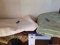 Folded ivory-cream and light green tablecloths on shelf