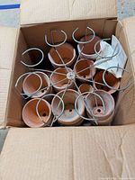 Box with stacked terracotta pots, metal holder on top, instruction sheet visible