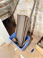 Blue tote containing shelving panels, uprights, and miscellaneous items