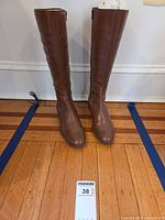 Front view of the brown leather knee-high boots standing upright