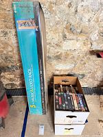 Boxed Atlantic rack next to two cardboard boxes of VHS tapes