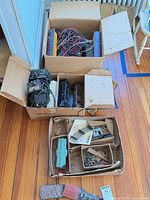 Overview of three cardboard boxes containing locomotive, cars, transformer, wiring, track, and inserts