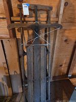 Front view of sled showing wood slats, metal runners, steering crossbar, attached rope