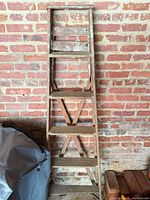 front view of full wooden ladder leaning against brick wall