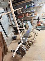 Overall Weider bench with attachments, barbell, dumbbells, plates visible