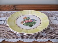 Yellow round plate with floral centre on lace cloth