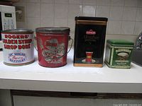 Front view of four vintage metal storage tins lined up side by side on counter