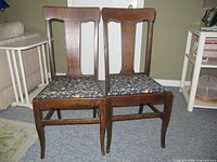 Front view of pair of antique wooden dining chairs with upholstered seats