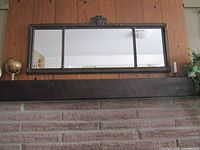 Front view of bronze-framed three-panel over-hearth mirror above fireplace
