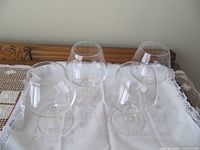 All four clear glass brandy snifters displayed upright on cloth