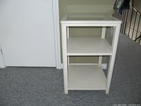 Square glass-top side table with two shelves shown from front angle