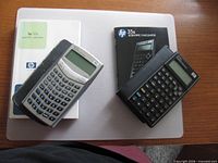 HP 33s and HP 35s calculators with their manuals and cases displayed together on tabletop
