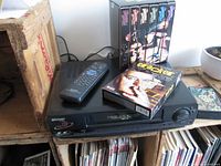 VCR with remote on top and six VHS tapes displayed